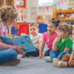 woman holding book and showing it to a group of young children