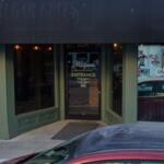 Green storefront with glass windows; left sign reads 'NATURE BITES', right sign 'CAFE', door in center labeled 'ENTRANCE' with a car parked outside.