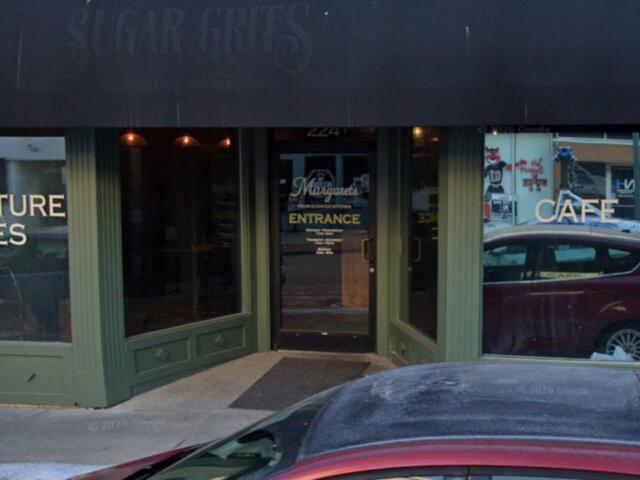 Green storefront with glass windows; left sign reads 'NATURE BITES', right sign 'CAFE', door in center labeled 'ENTRANCE' with a car parked outside.