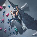 woman with curly hair climbs in bouldering gym