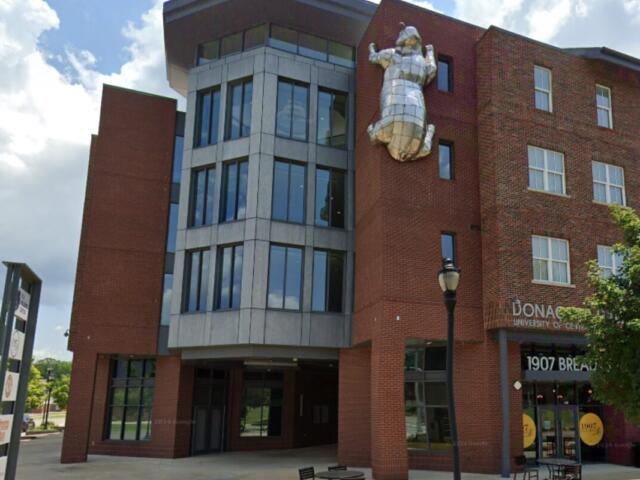 Brick university building with a large silver metal sculpture of a figure mounted on the wall.