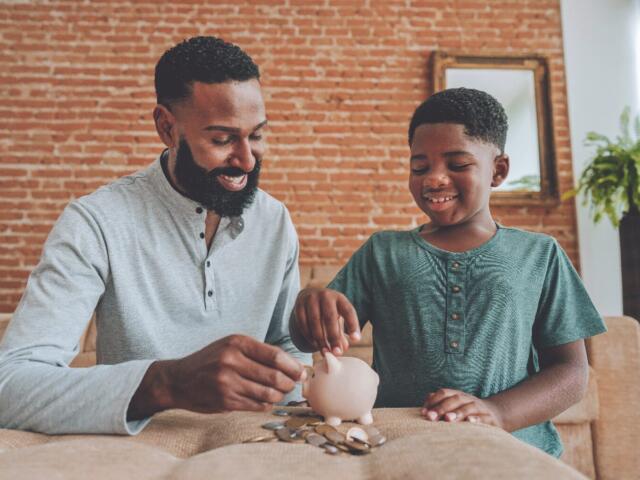 father and son putting pennies in piggy bank