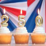 Three cupcakes with gold numeral candles 2, 5, and 0 against a patriotic red‑white‑blue backdrop.