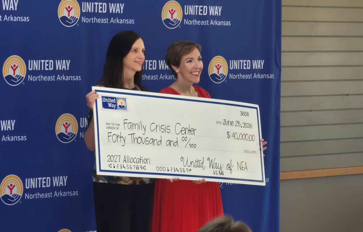 Two women pose with a large ceremonial check from United Way Northeast Arkansas in front of a blue backdrop with United Way logos.
