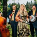 Five-member band outdoors: a woman in a metallic gold dress holding a violin, flanked by four men with a upright bass, violin, banjo, and guitar.
