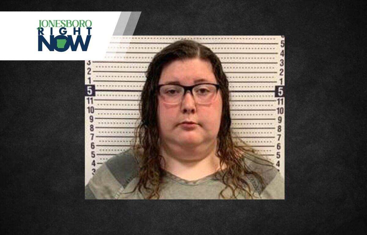 Mugshot-style photo of a woman with glasses in front of a height chart; Jonesboro Right Now logo in the corner
