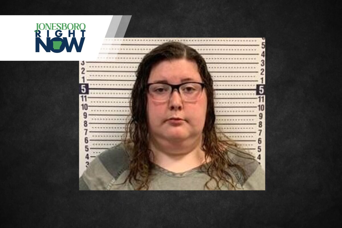 Mugshot-style photo of a woman with glasses in front of a height chart; Jonesboro Right Now logo in the corner