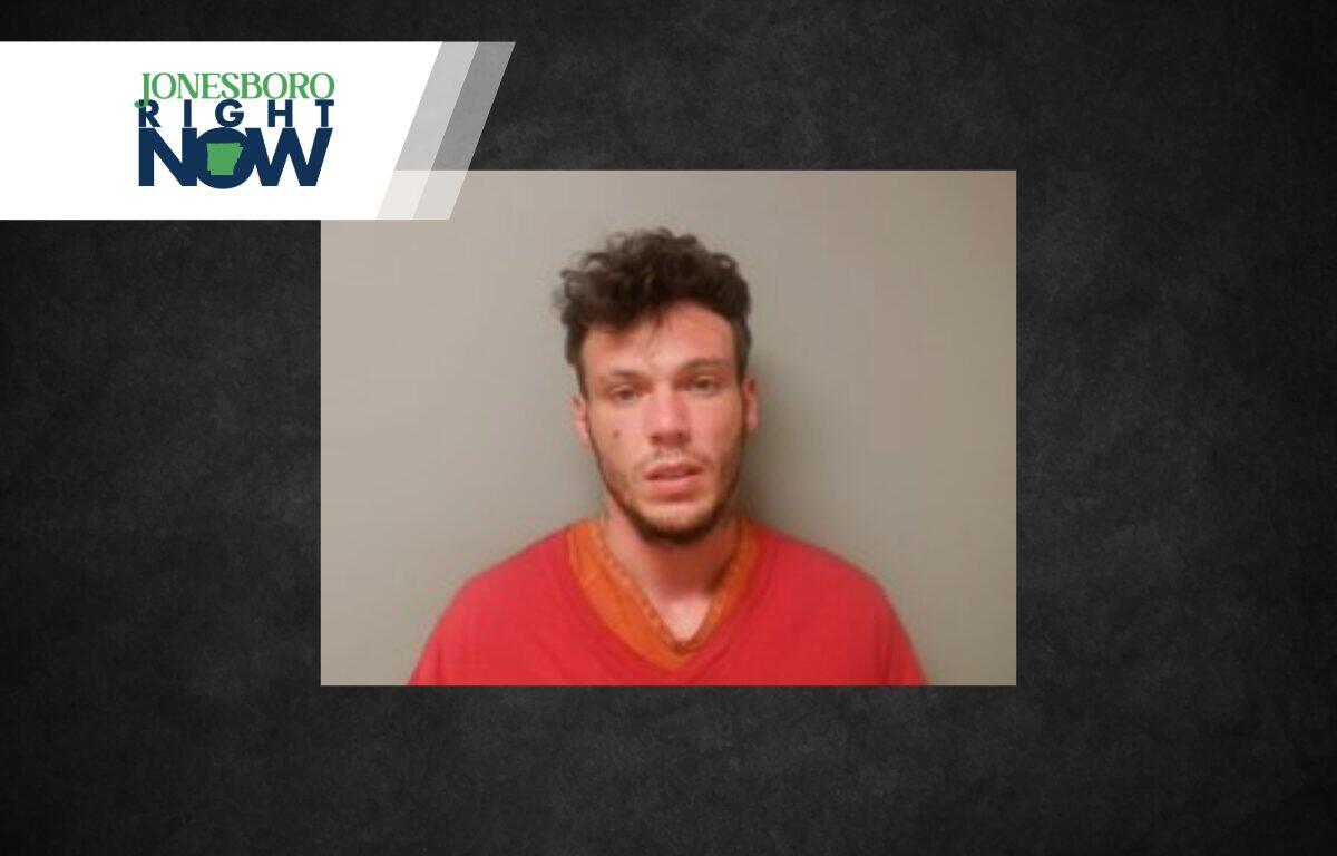 Mugshot-style photo of a young man wearing a red shirt against a gray wall, with a Jonesboro Right Now news banner in the corner.
