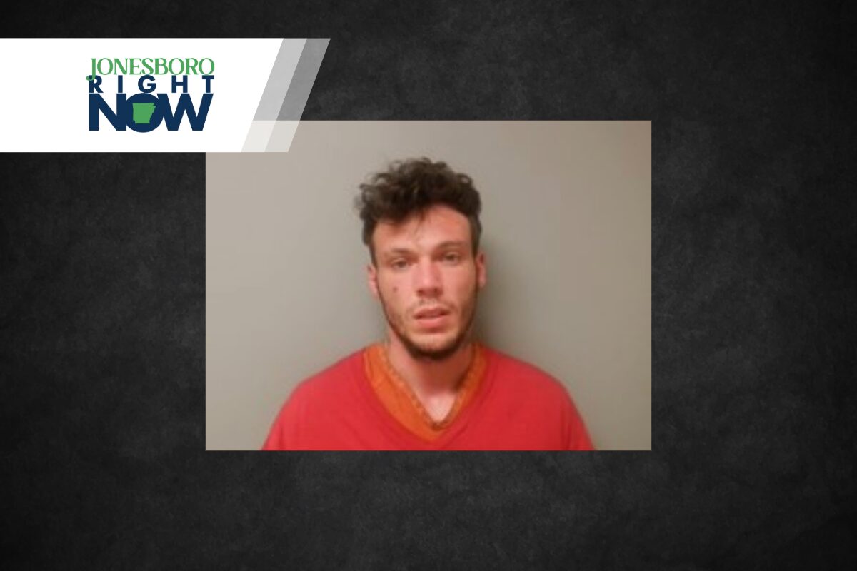 Mugshot-style photo of a young man wearing a red shirt against a gray wall, with a Jonesboro Right Now news banner in the corner.