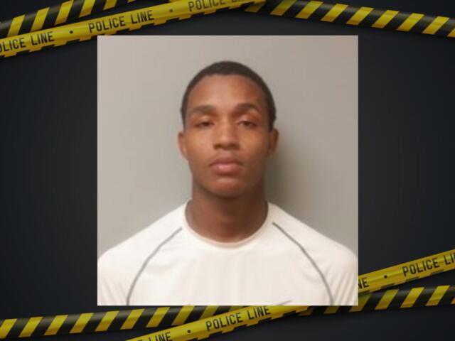 Mugshot of a young man with short hair wearing a white shirt, neutral expression, gray wall background, police tape border framing the image.