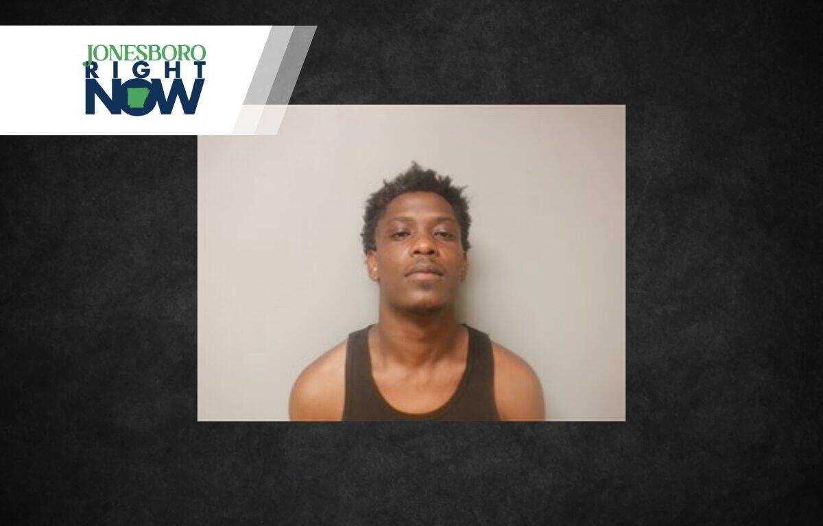 Mugshot-style photo of a young man in a black tank top against a gray wall, with a Jonesboro Right Now logo in the upper left corner.