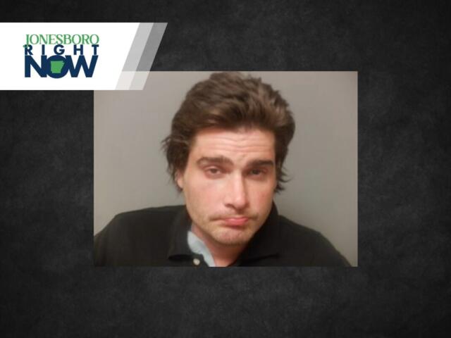 Mugshot-style photo of a disheveled man with brown hair wearing a dark polo, on a gray background, with a Jonesboro Right Now logo in the top-left corner.