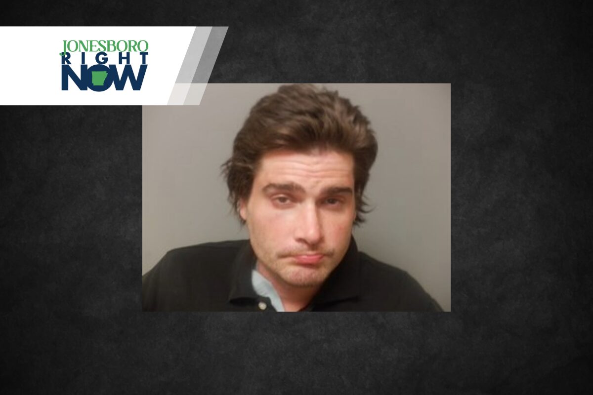 Mugshot-style photo of a disheveled man with brown hair wearing a dark polo, on a gray background, with a Jonesboro Right Now logo in the top-left corner.