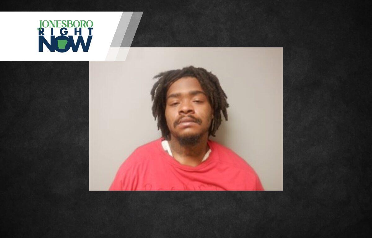 Mugshot-style photo of a man with dreadlocks wearing a red shirt, neutral background, Jonesboro Light Now logo in the top-left corner.