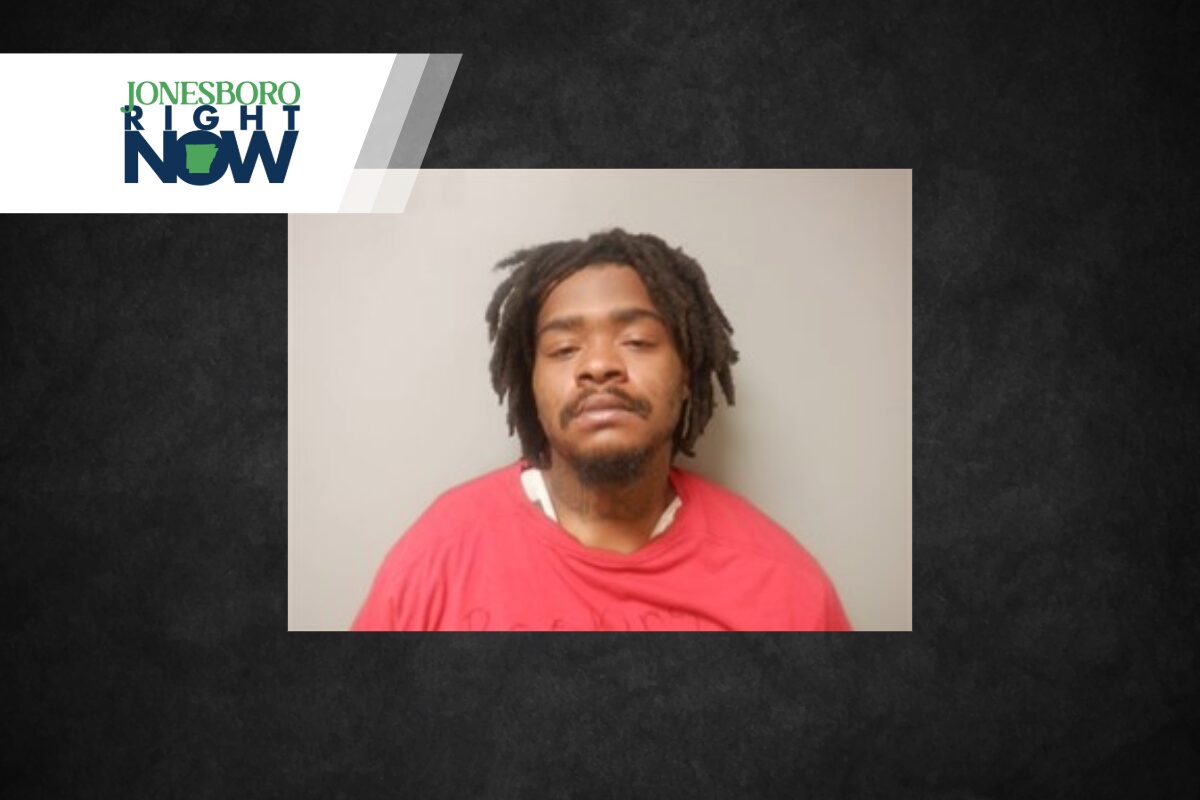 Mugshot-style photo of a man with dreadlocks wearing a red shirt, neutral background, Jonesboro Light Now logo in the top-left corner.