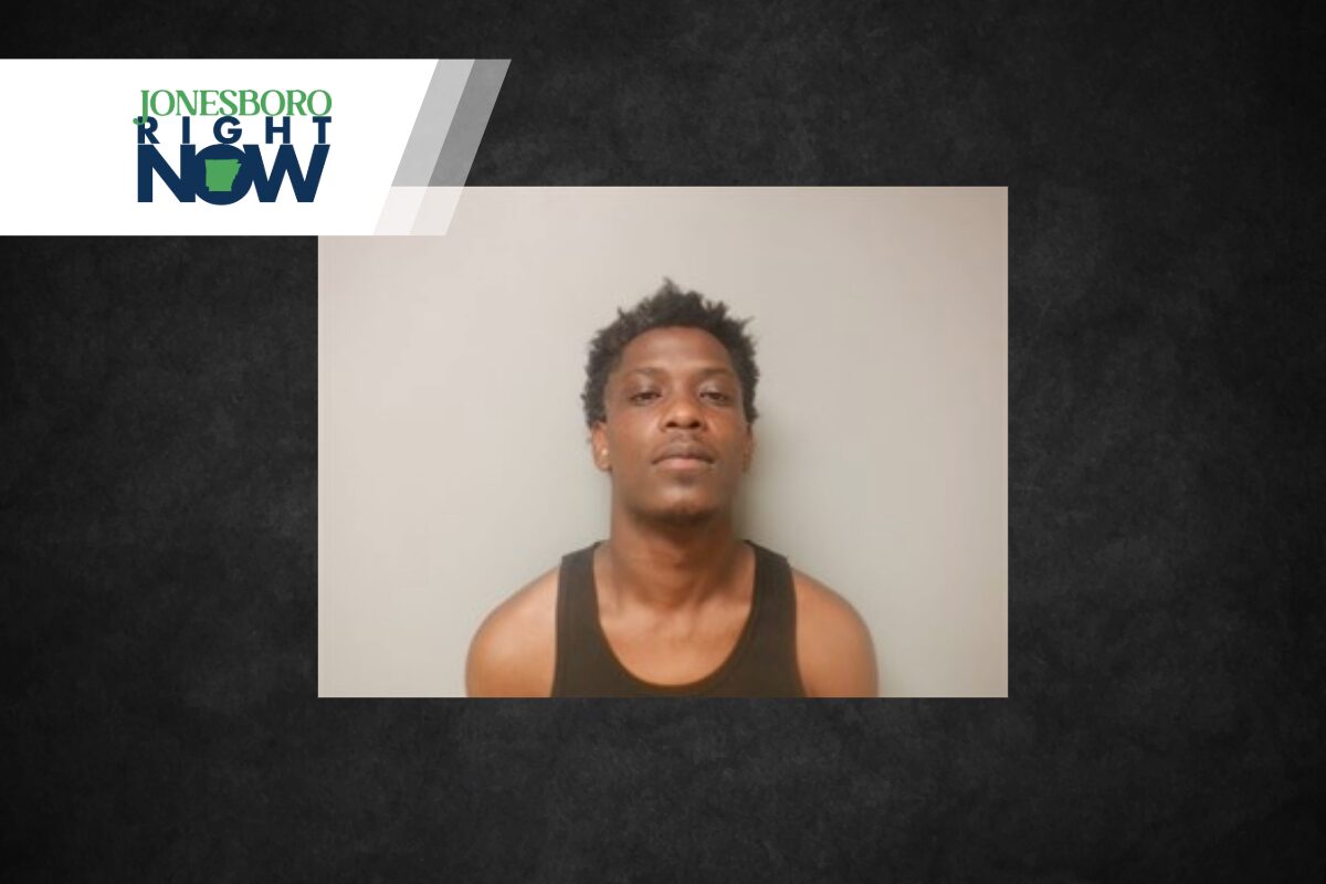 Mugshot-style photo of a young man in a black tank top against a gray wall, with a Jonesboro Right Now logo in the upper left corner.