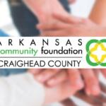 Arkansas Community Foundation Craighead County logo with hands stacked in a circle in the blurred background behind it.
