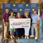 Five adults pose with an oversized ARVEST Foundation check for $5,000 to the Single Parent Scholarship Fund, in front of a branded backdrop.