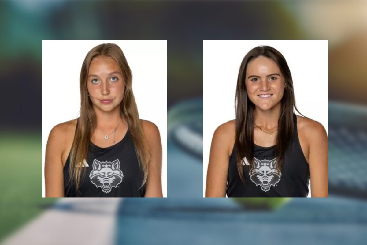 Two young women in black tank tops with a wolf logo, white background; left: light brown hair, neutral expression, right: dark brown hair, smiling.