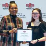 Two women pose with a scholarship certificate at an Arkansas State University backdrop (College of Liberal Arts & Communications).