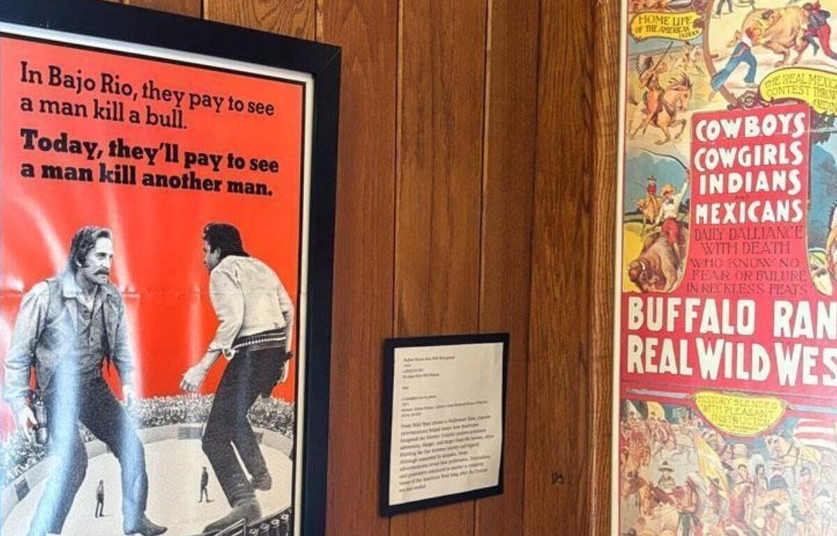 Framed vintage posters on wood panels, one red text poster depicting a bullfight scene and a Western-themed poster to the right