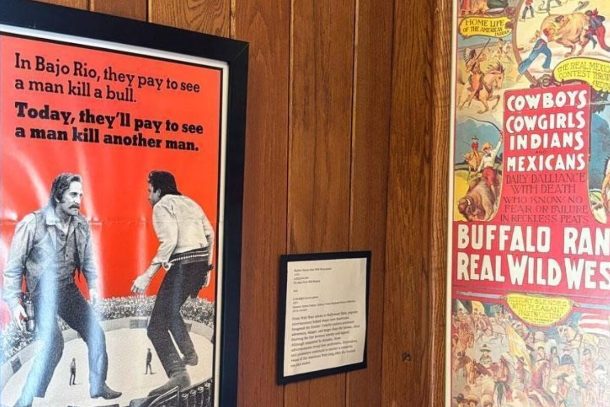 Framed vintage posters on wood panels, one red text poster depicting a bullfight scene and a Western-themed poster to the right