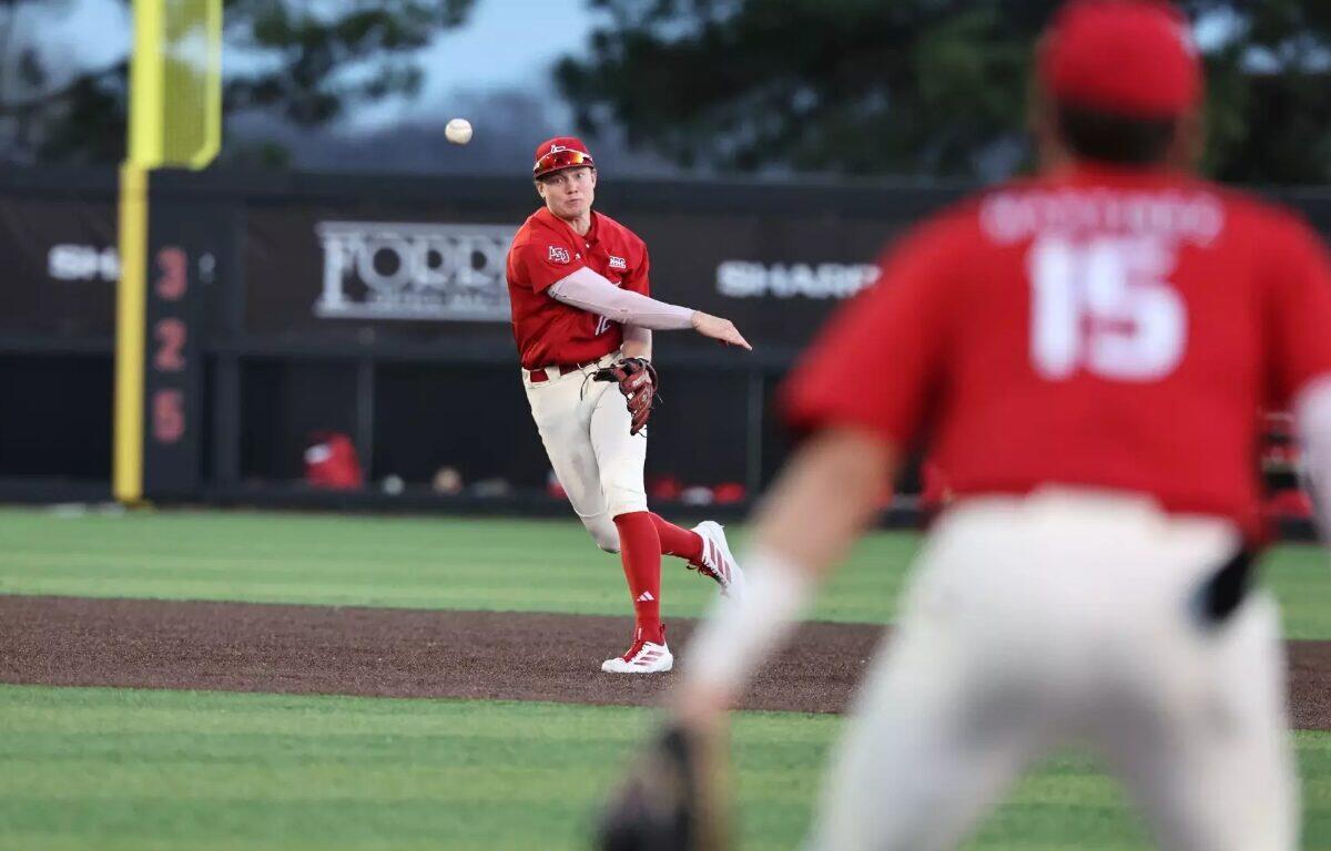 Baseball pitcher in red uniform throws a pitch on the mound, with a fielder in foreground wearing number 15 blurred in the foreground.