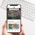Handheld smartphone displaying a mobile news app with a headline about EBT fraud protections and a 'Latest Stories' section.