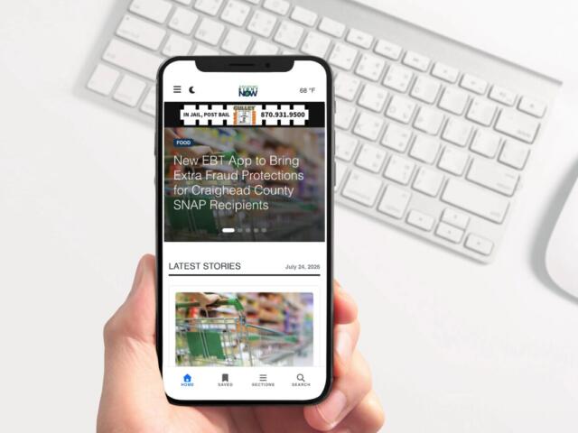 Handheld smartphone displaying a mobile news app with a headline about EBT fraud protections and a 'Latest Stories' section.