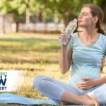 Pregnant or exercises woman sitting cross‑legged on a yoga mat in a park, sipping water with eyes closed; Jonesboro Right Now logo in the lower left corner.