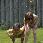 Kids find a water sprinkler to cool off