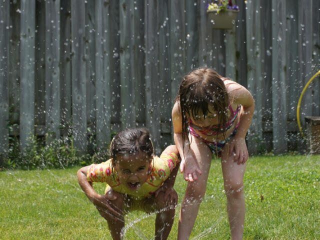 Kids find a water sprinkler to cool off
