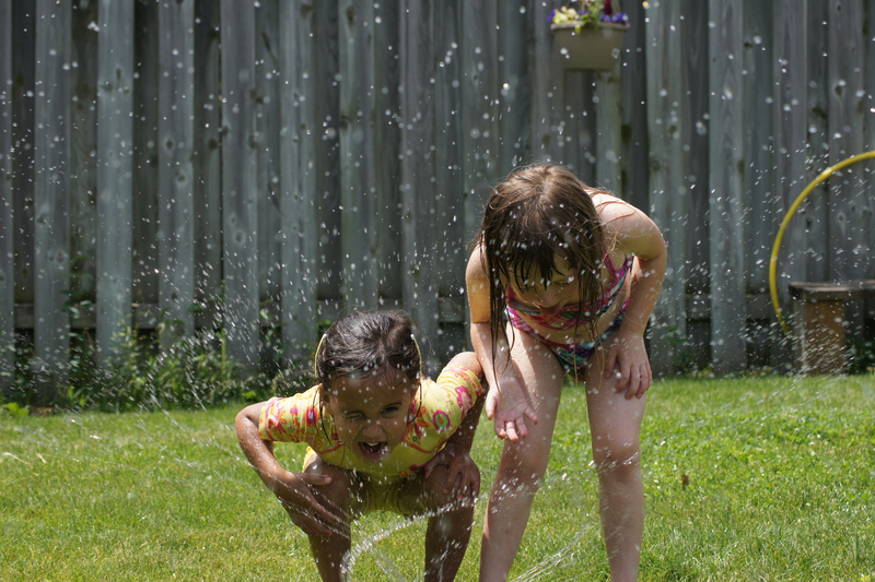 Kids find a water sprinkler to cool off